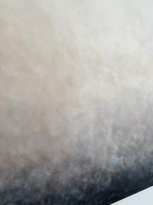 Närbild tagen snett från sidan på en abstrakt tavla med mjuka skiftningar mellan svart, grå, beige och vit